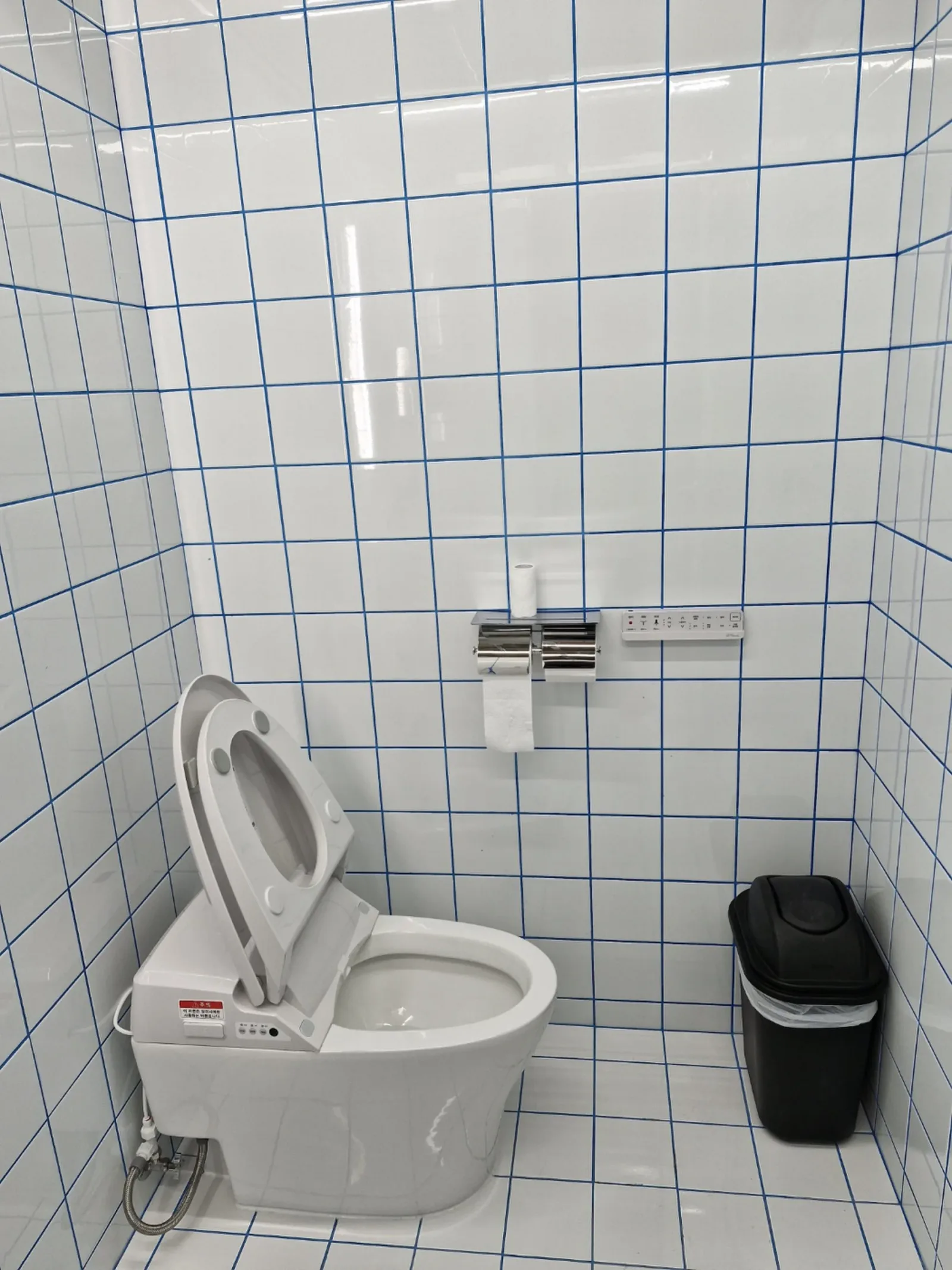 흰색 사각 타일에 파란색 줄눈이 시공된 화장실 벽·바닥이 잔사 없이 깨끗하게 마감된 사진